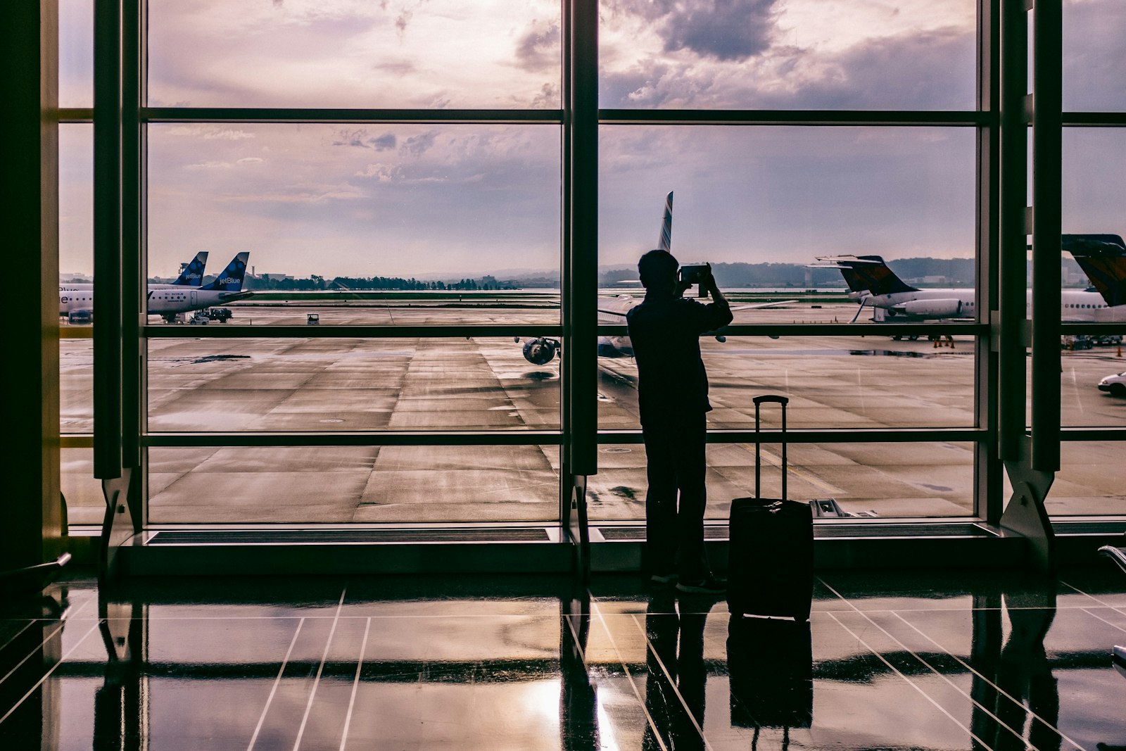空港の窓辺で飛行機を眺める人のシルエット